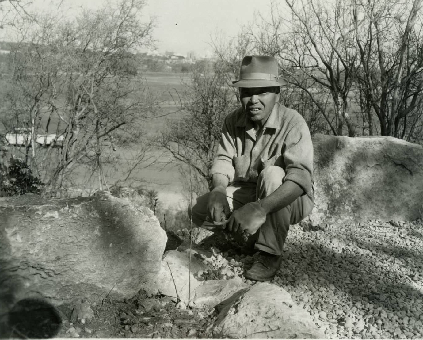 Garden architect and builder Isamu Taniguchi kneeling at Oriental Garden, 1968