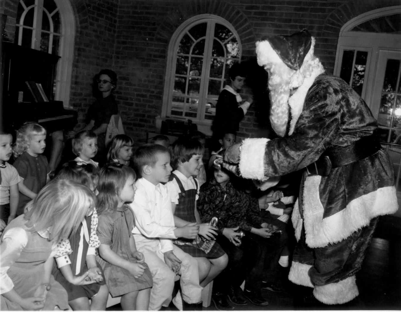 A Tiny Tot Christmas Party at Hancock Recreation Center. Santa Claus hands out candy canes to a group of children, 1966