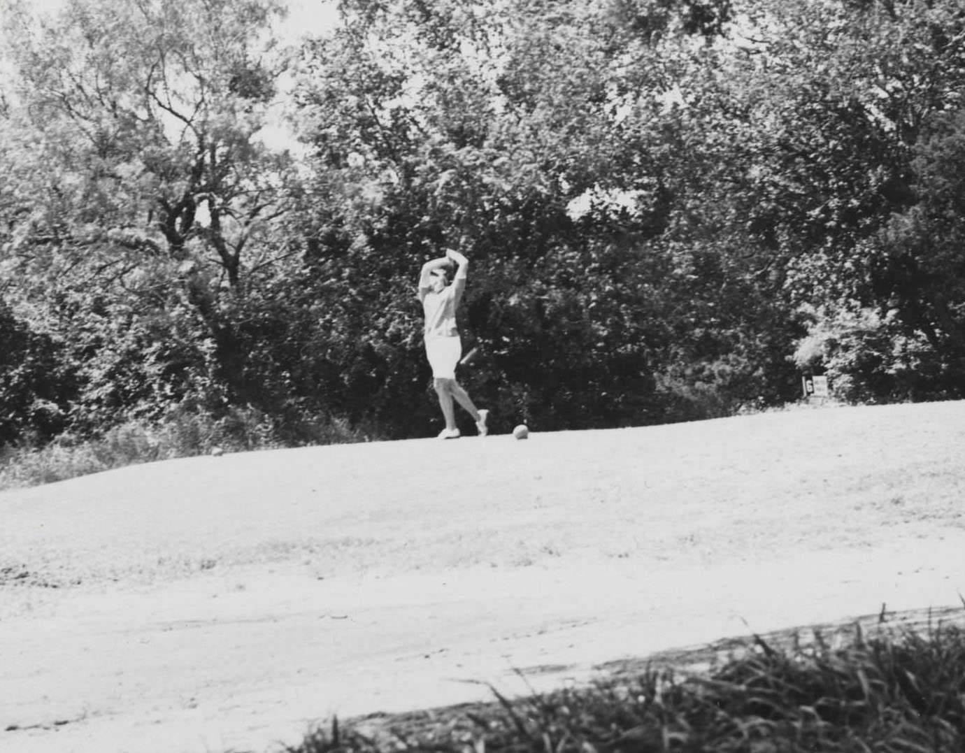 A golfer swinging on a drive at the AWPLGA tournament at the Austin Municipal Golf Course, 1966