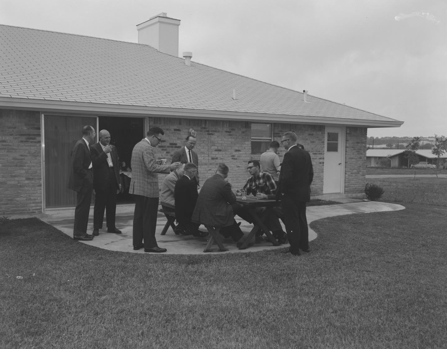 A group of men around a picnic table at a Friday night cocktail party, Austin, 1961