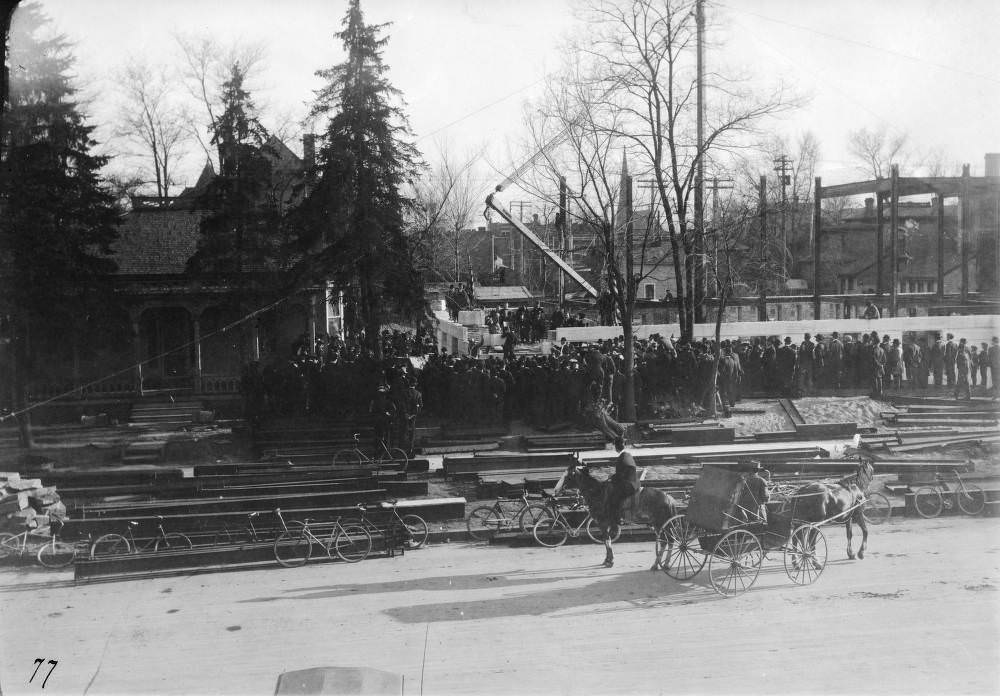 People crowd the Denver Public Library (Carnegie) construction site by a crane to watch the cornerstone ceremony in the Civic Center neighborhood of Denver, 1900