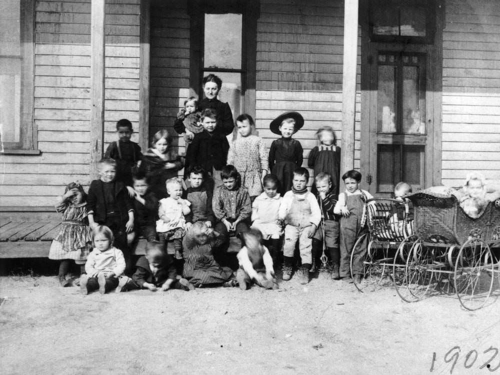 Children and a woman stand on the porch of the Neighborhood House Association building at 962 Santa Fe in the Lincoln Park neighborhood of Denver, 1902