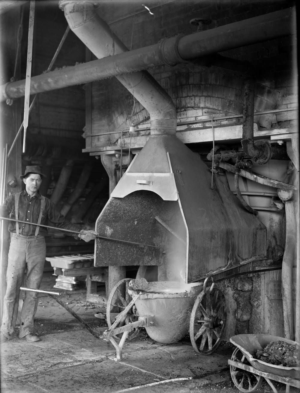 A worker draws slag from an oven or furnace in the Omaha-Grant smelter in Denver, 1900