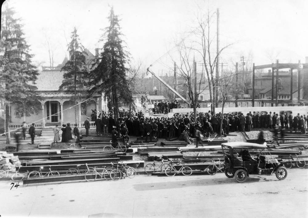 People crowd the Denver Public Library (Carnegie) construction site by a crane to watch the cornerstone ceremony in the Civic Center neighborhood of Denver, 1900s