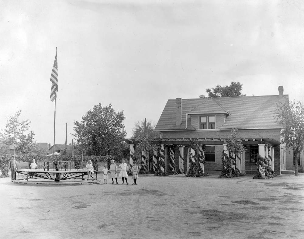 Children pose on and near a merry-go-round in Elyria Park playground in Denver, 1909