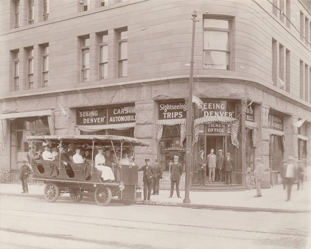 Employees pose by a "Seeing Denver" electric tour coach at 17th (Seventeenth) Street and Tremont Street in Denver, 1900