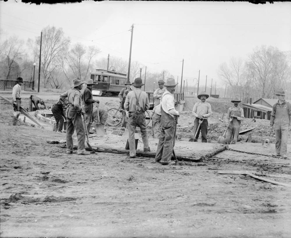 Workmen pour concrete into forms for a gutter near the Alameda Avenue bridge in Denver, 1909