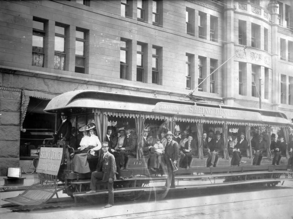 Passengers, conductors, and a tour guide with a megaphone ride on Denver Tramway Company trolley number 112 in Denver, 1900