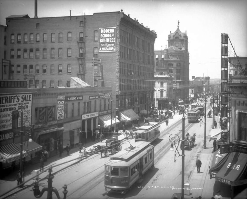 View of 15th (Fifteenth) on a busy day; shows electric street railway cars (or trolleys including car number 358), horse-drawn wagons and carriages, bicycles, men and women on sidewalk and the Mining Exchange Building, 1909
