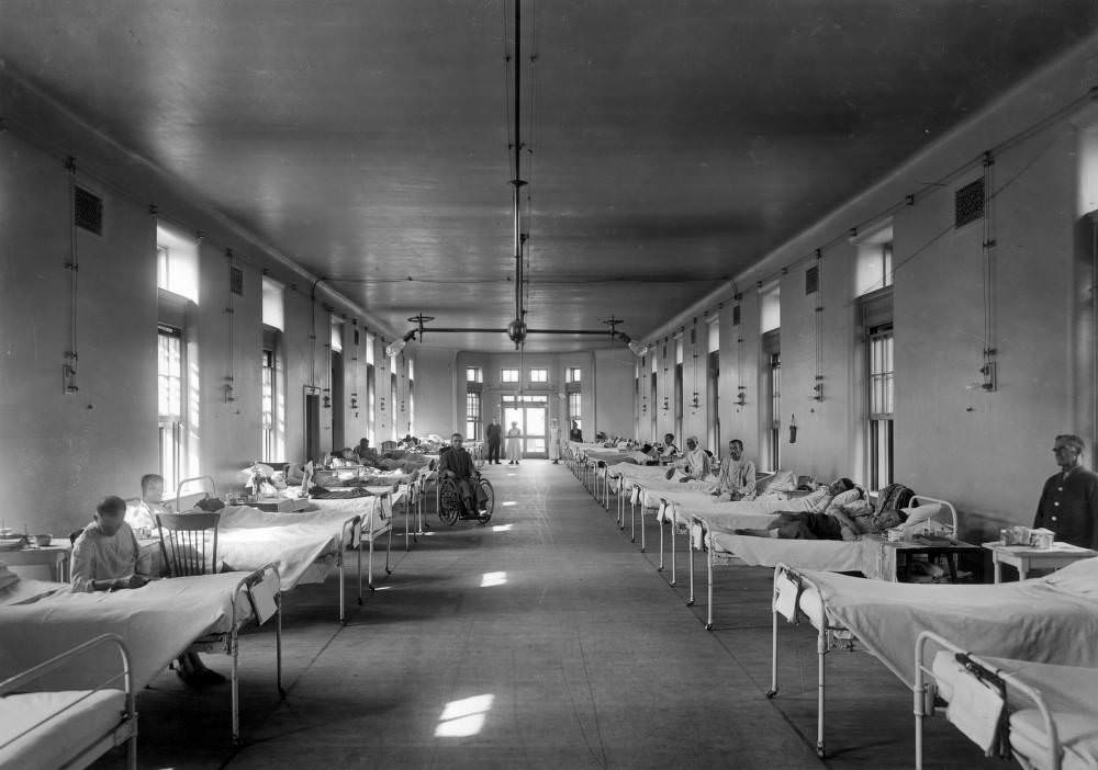 Sick men lie in beds and sit in wheelchairs in the Tuberculosis Ward of Denver General Hospital in Denver, 1900