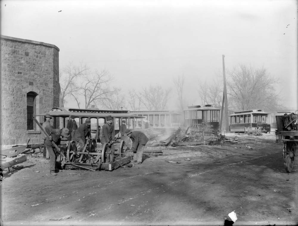 Workers dismantle the chassis and wheels from several old Denver Tramway Company cars in Denver, 1909