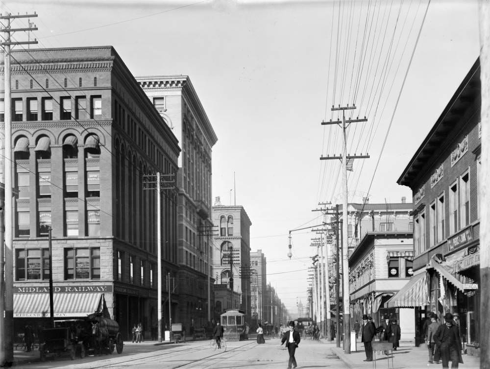 View of 17th (Seventeenth) Street in Denver, Colorado. Pedestrians walk on the sidewalk and in the street. Denver City Tramway Company street car number 232 makes its way north, 1909