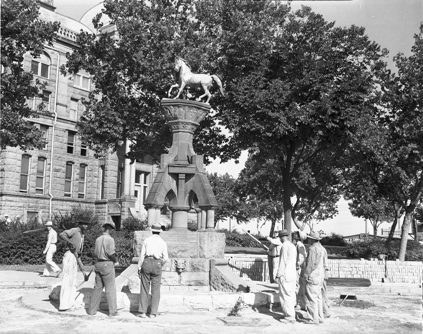Workmen looking at 48-year-old horse trough on Courthouse Square, downtown Fort Worth, 1940