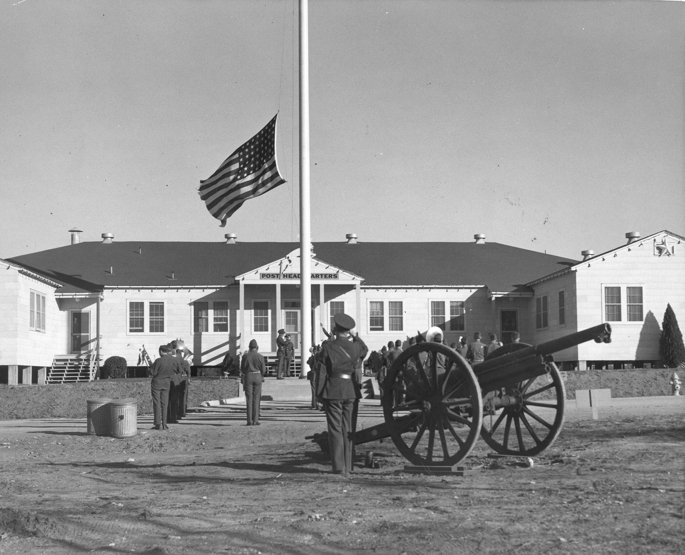 Retreat soldiers saluting lowering of flag as cannon booms, 1943