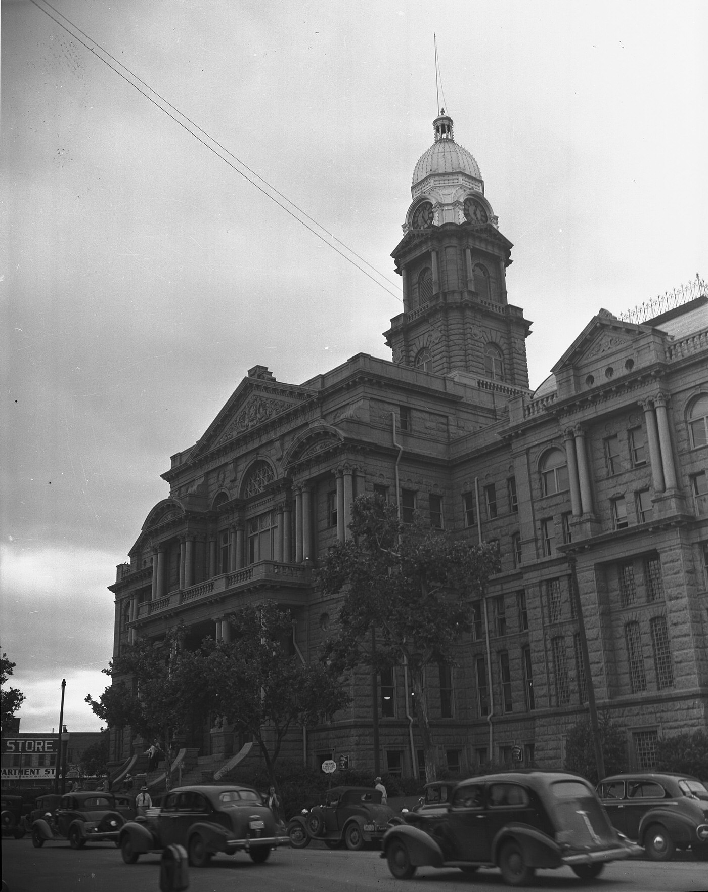 Exterior of the Tarrant County Courthouse with 1930s cars on street in front of building, 1940