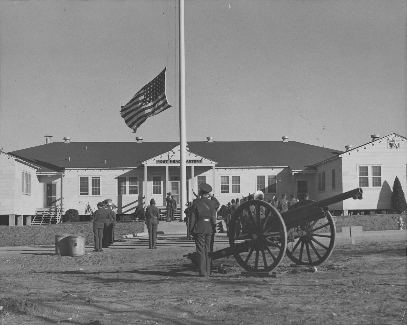 Soldiers fire a cannon during lowering of an American flag in front of the post headquarters building, Tarrant Army Air Field (later renamed Carswell Air Force Base), Fort Worth, Texas, 1943