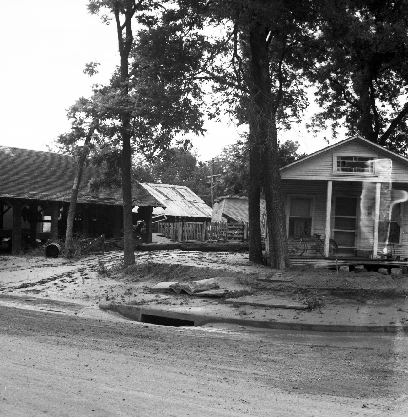 Damaged houses and debris on road from flood, 1949