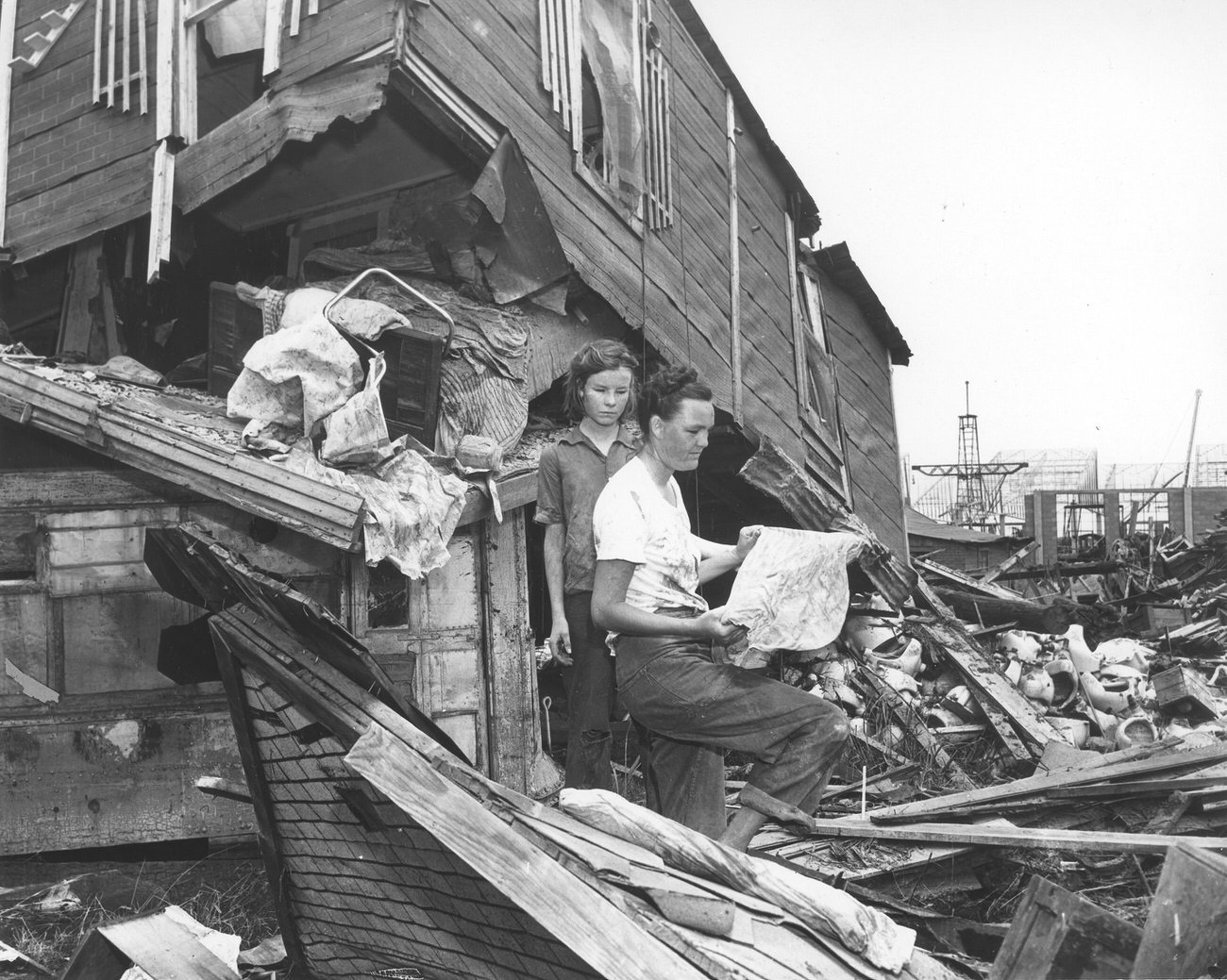 Mother and daughter standing beside flood-destroyed home, Fort Worth, 1949.