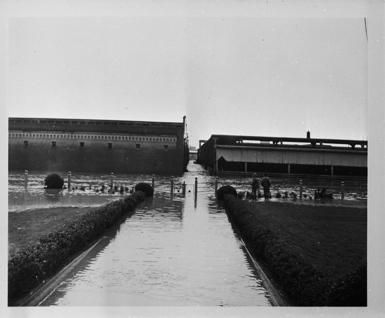 The Fort Worth Stockyards after a flood. Two men are standing by a fence looking at the damage.