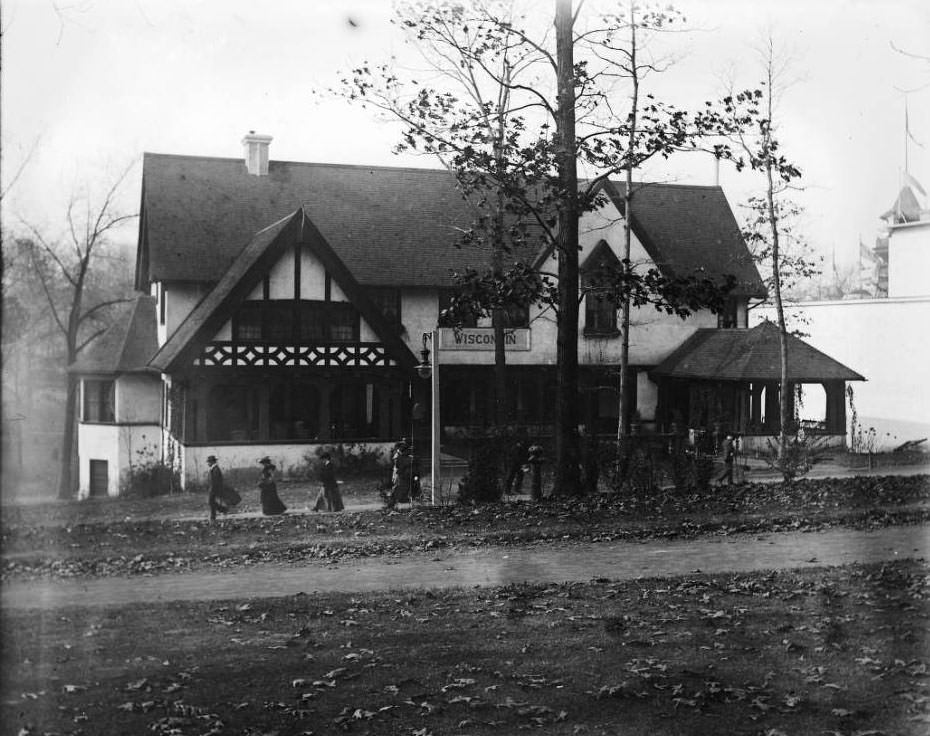 Autumn leaves are on the ground, as fairgoers visit the Wisconsin pavilion at the Louisiana Purchase Exposition, 1904