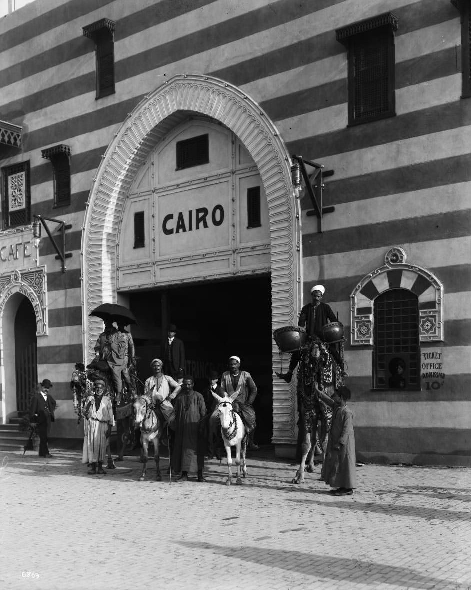 Egyptians on camelback and donkeys pose before the entrance to the Cairo concession on the Pike, 1904