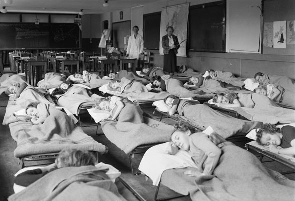 Kids sleeping on cots at the Wilkinson Open Air School. Outdoor educational facilities were established to help combat tuberculosis on the assumption fresh air and good ventilation would be beneficial to health, 1940s