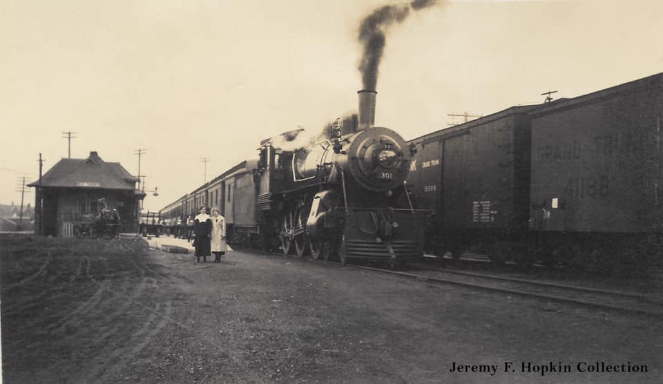 Two ladies have their picture taken beside a train at the Grand Trunk Railway's West Toronto station, 1910s.