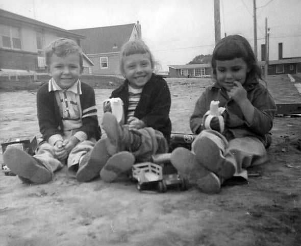 three young friends eating bananas and sitting on the ground in front of 5 Sherwood Ave. in Scarborough, 1956