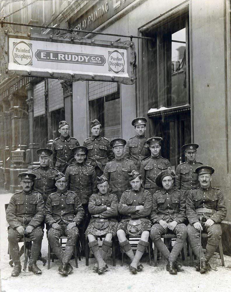 Group of soldiers posing during a snow storm in front of the offices of E.L. Ruddy Company Limited, 1900s