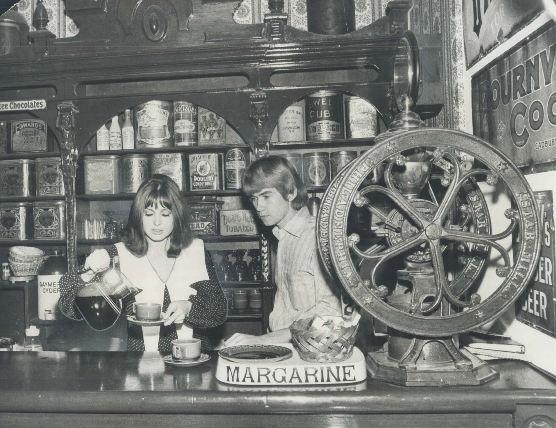 Surrounded with antiques; Joy and Neil Dixon preside at the counter of their coffee house; Grumbles; at 71 Jarvis St., 1970