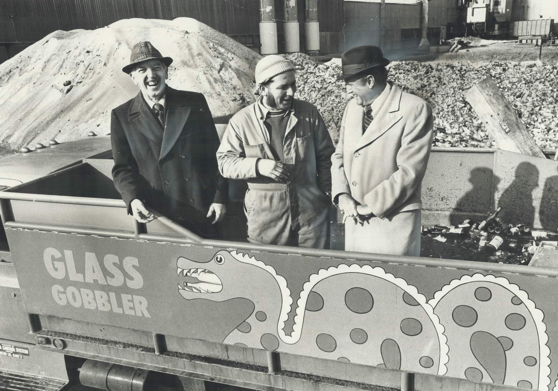 Early recycling - Three men in the truck are pointing to the name on the side; Glass Gobbler; which defines its job, 1977