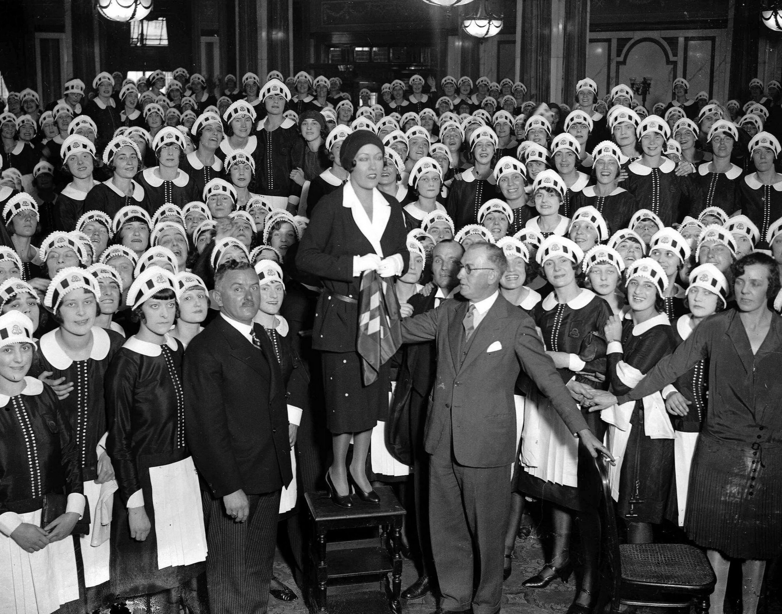 Gloria Swanson talks to a huge crowd of "Nippies" (waitresses at Lyon's corner house)