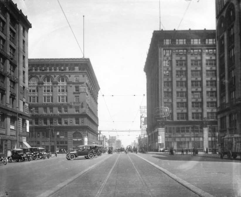 The intersection of North Tucker Boulevard and Washington Avenue. Automobiles, pedestrians and horse-drawn wagons are visible, there are many pedestrians along Washington Avenue, 1910