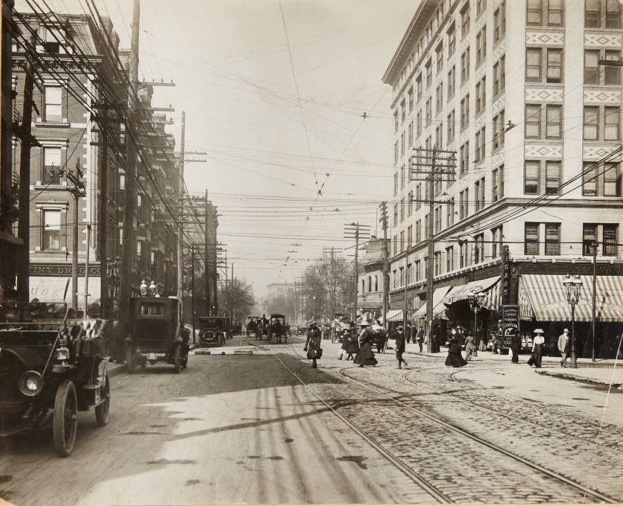 A busy scene of pedestrian and equine traffic at the intersection of Grand and Olive, looking north on Grand, 1910