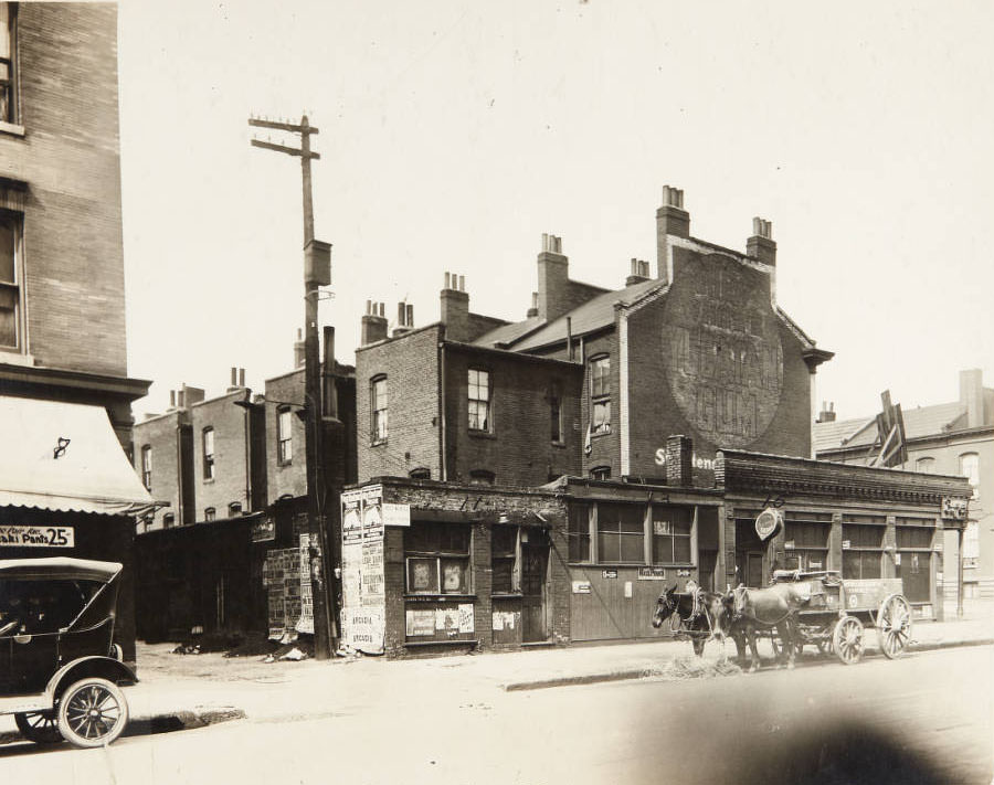 A team of horses taking a break in front of a row of buildings on 20th Street, 1915