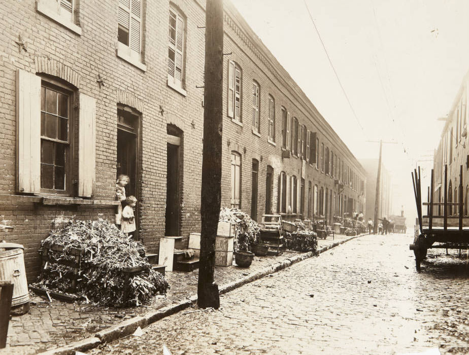 A long rowhouse along an unidentified cobblestone street, 1915