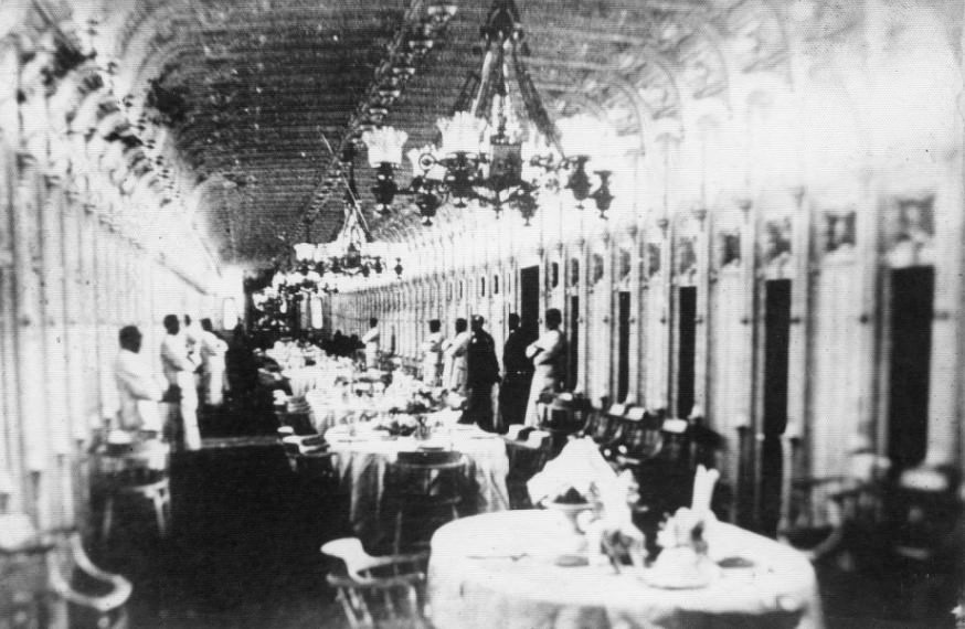 Cabin of the City of Baton Rouge, with workers leaning against the walls and tables set for meal service, 1880