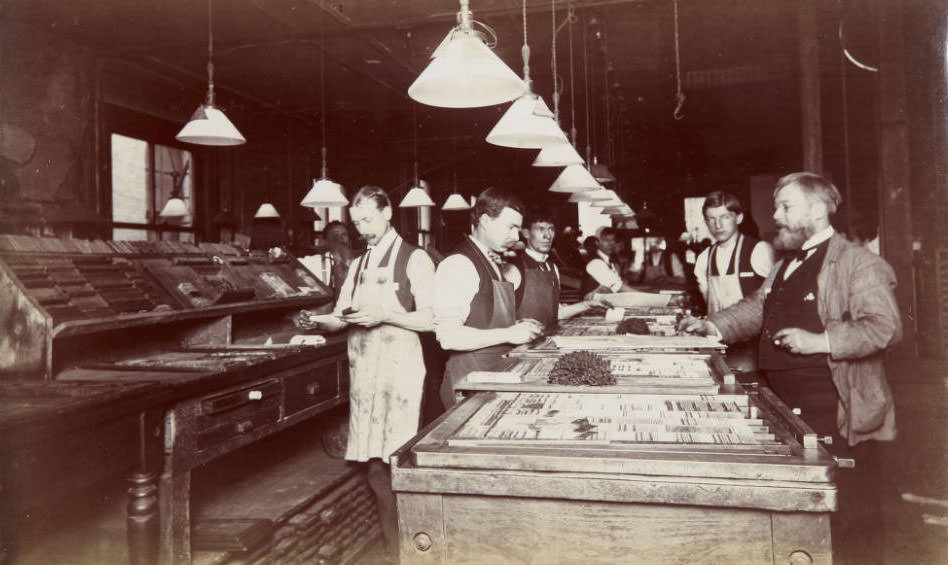 Several men setting type by hand in a large workroom, 1899