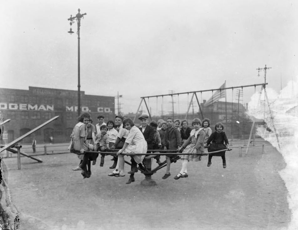 Large group of children pose for the camera while sitting on a playground merry-go-round, 1925