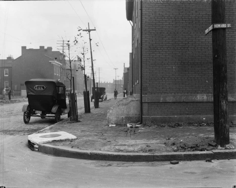 Brick rowhouses and sidewalk, includes two cars and pedestrians, 1925