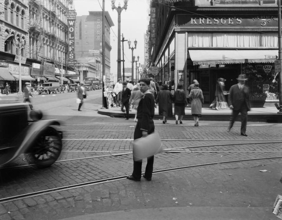 View of a young man crossing Sixth street at Washington. Kresge's is across the street, 1925