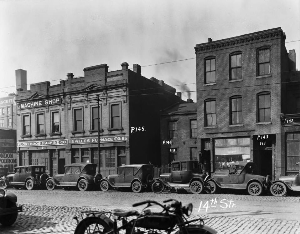 View of the buildings whose addresses were 111, 113, 115, 119 14th Street and cars parked in front, 1925