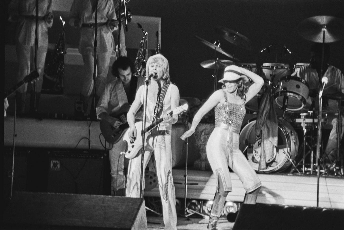 Björn Ulvaeus and Norwegian-Swedish singer, songwriter, and environmentalist Anni-Frid Lyngstad of pop group ABBA performs on stage at the Royal Albert Hall, London, UK, 15th February 1977.