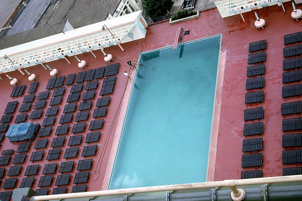 Hotel workers are up early to clean a swimming pool before all the guests descend to swim and lie on the sun loungers