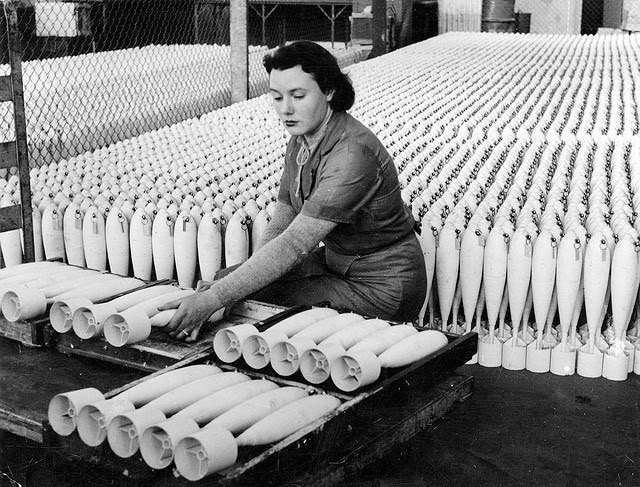 A woman stacking practice bombs before transit to the explosives filling factory in South Australia.