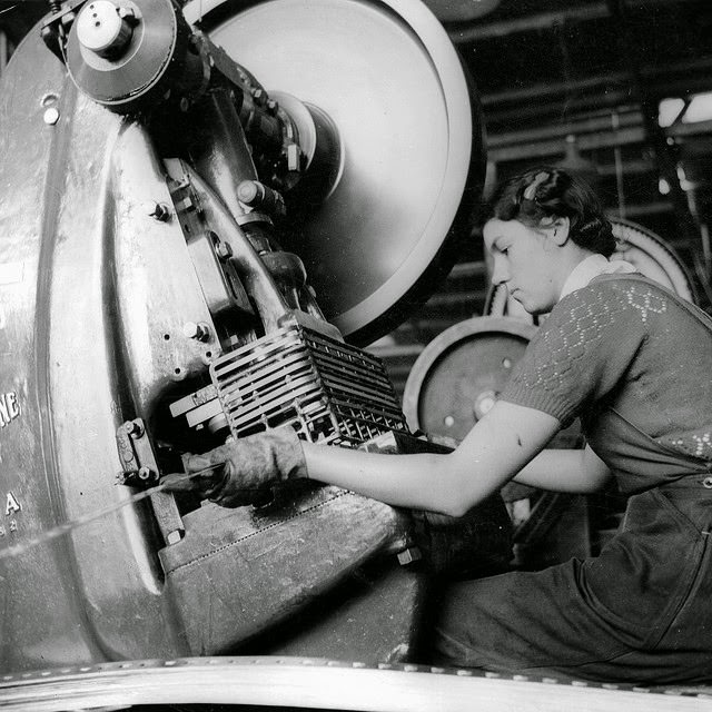 A young woman working at a small press making ammunition boxes.