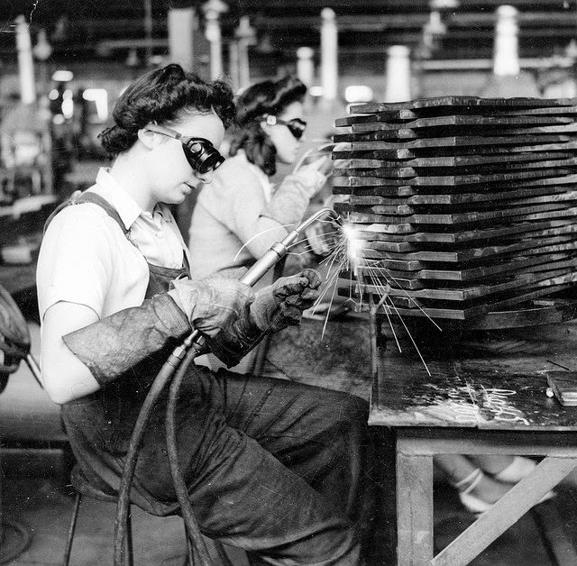 Two young women oxy welding parts of ammunition boxes.