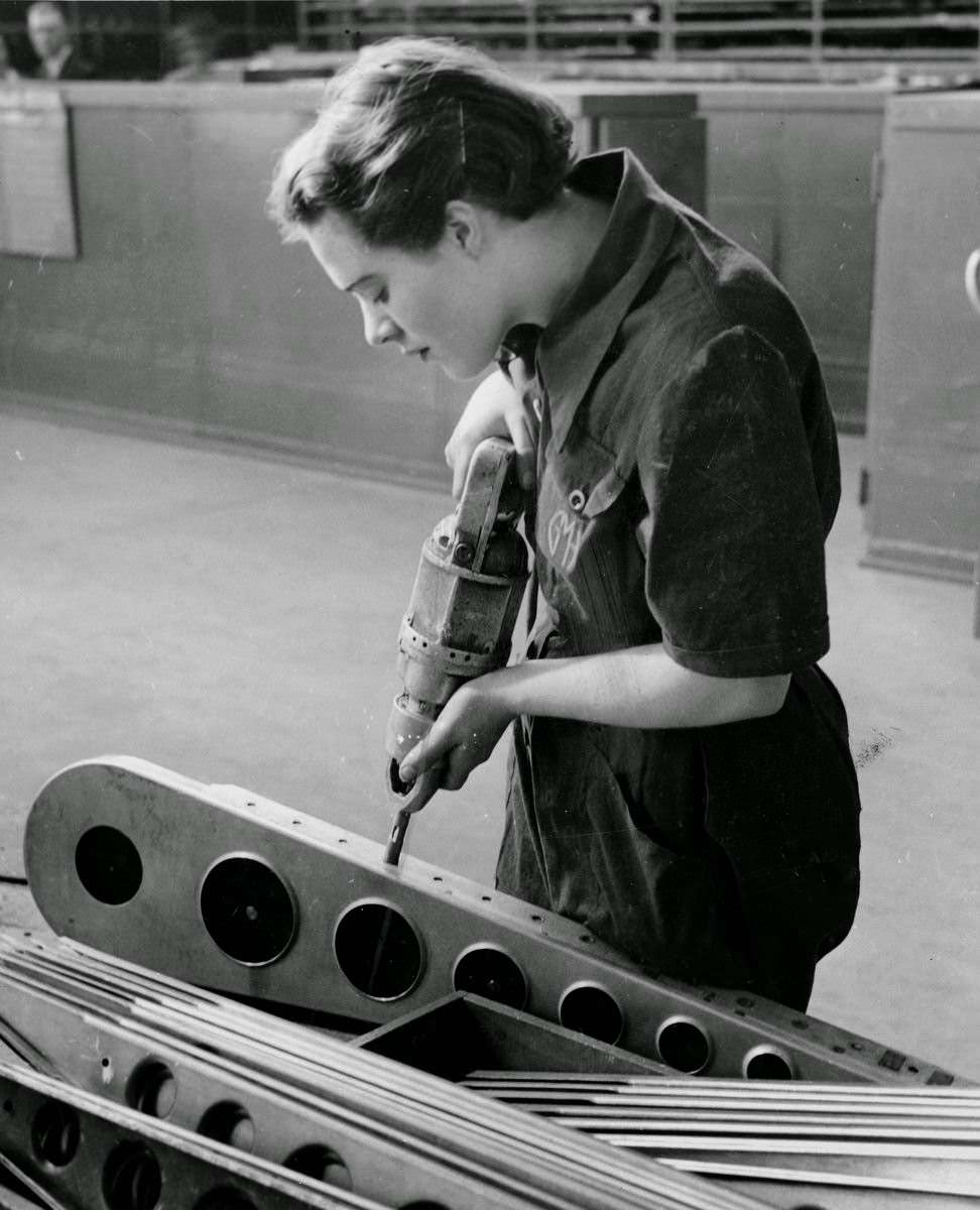 A young woman drilling parts of a Beaufort bomber with a portable drill.