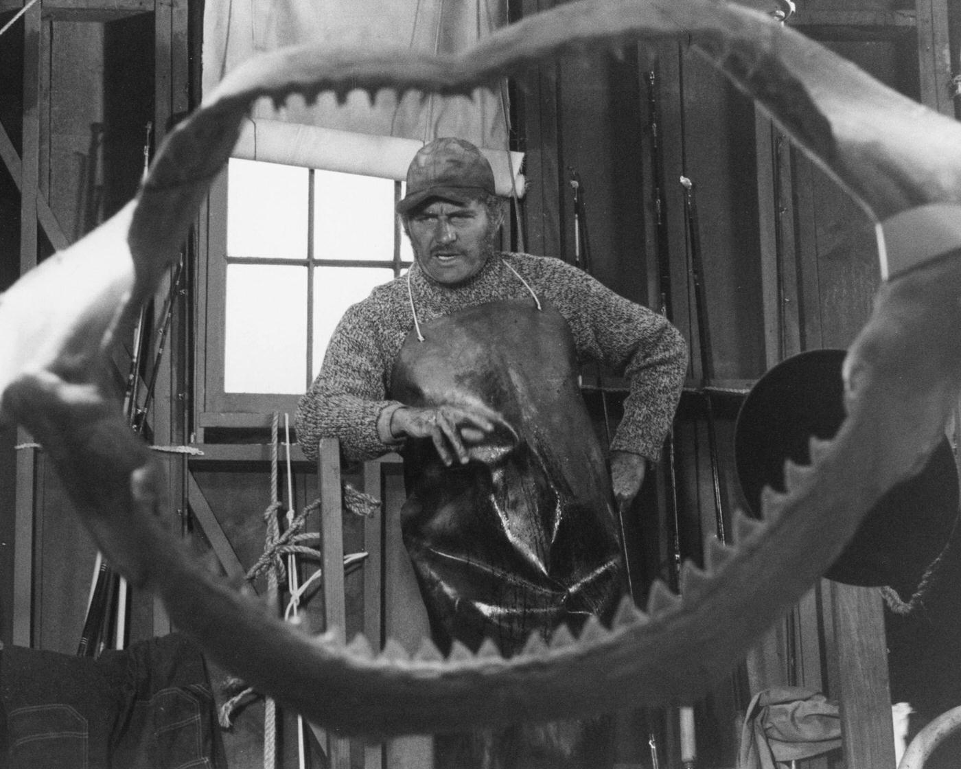 English actor Robert Shaw as Quint, viewed through a set of shark jaws, in a publicity still for 'Jaws', 1975.