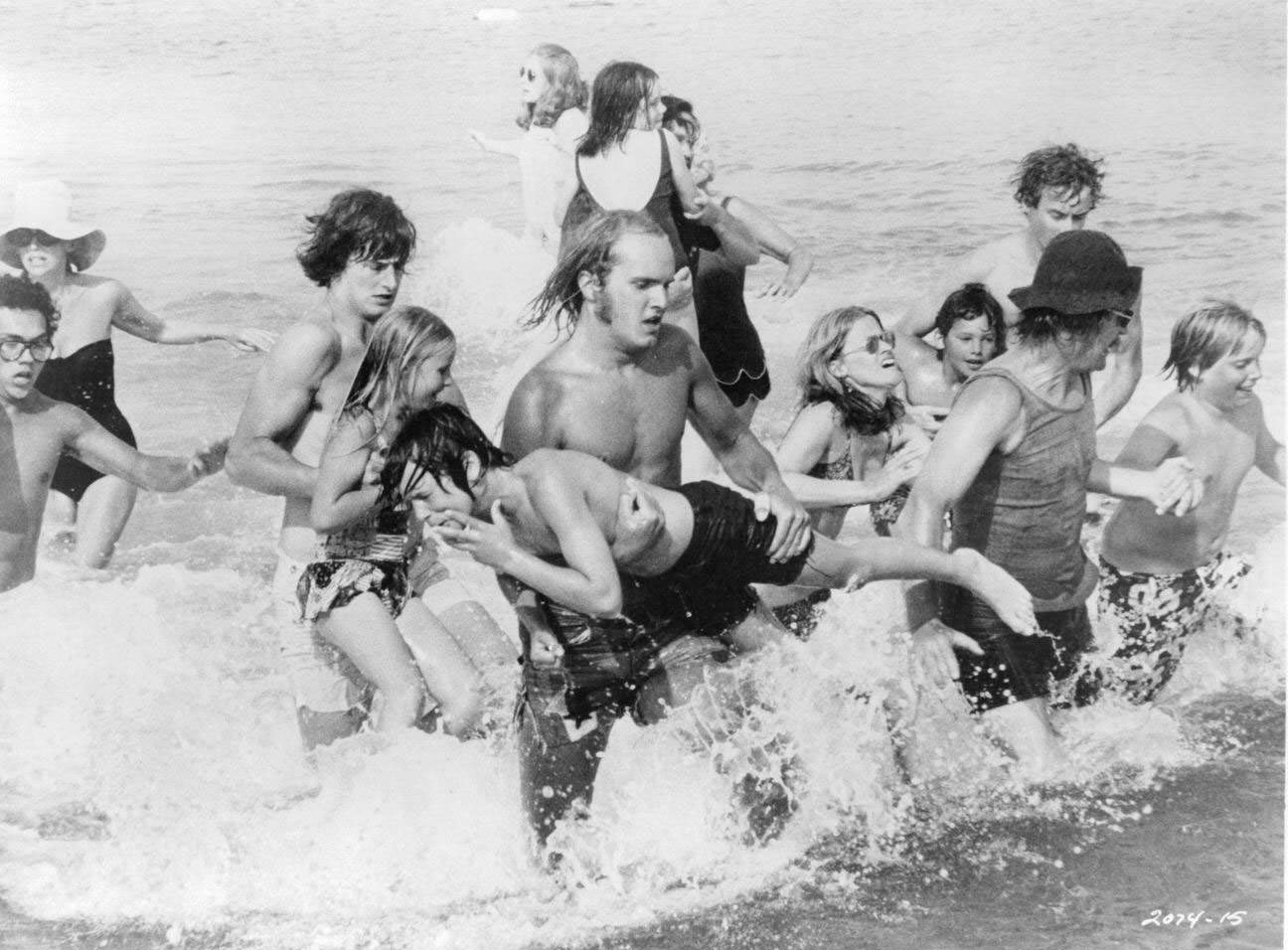 A group of actors are running out of the ocean in a panick in a scene from the film 'Jaws', 1975.